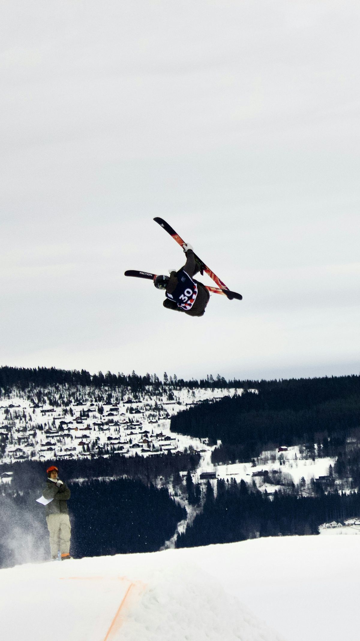 Freestylekjører gjør hopp over snødekt alpinlandsby en vinterdag