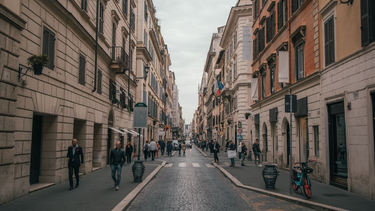 Smal brosteinsgate i Roma med historiske bygninger og fotgjengere